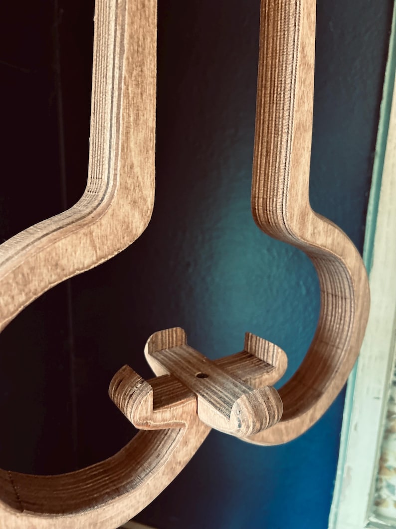 May include: A wooden wall-mounted phone holder shaped like an airplane. The holder is made of plywood and has a natural wood finish.