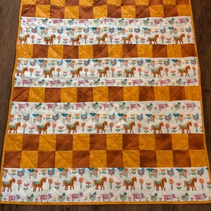 Patchwork deken met boerderijdieren, paarden, koeien, varkens, kippen, bruine en gouden lapjes.