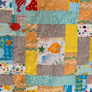 Sea creatures are featured in this adorable quilt with waves on the coral fabric on the back. Perfect for nap time, play time and the beach!