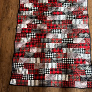 Red, black and white plaid flannel bricks stack up in this cozy quilt. The red and black plaids are the perfect pop of color for any room.