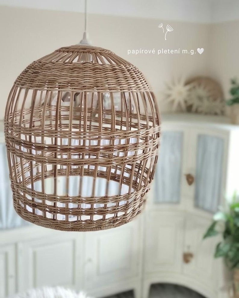 Może przedstawiać: Pleciona lampa wisząca z wikliny z białym wnętrzem. Lampa jest zawieszona na białym kablu i znajduje się w pokoju z białymi meblami.