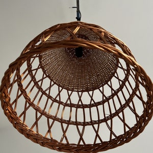 May include: A brown wicker pendant light fixture with a woven design. The light fixture is hanging from a white ceiling.