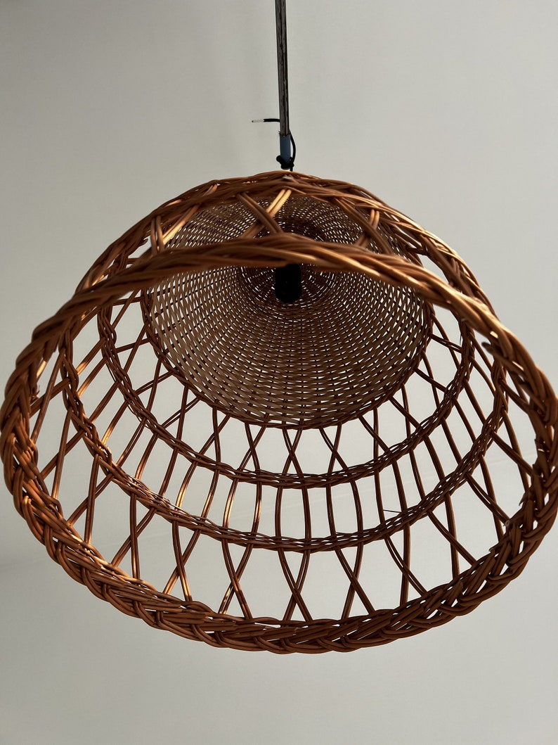 May include: A brown wicker pendant light fixture with a woven design. The light fixture is hanging from a white ceiling.