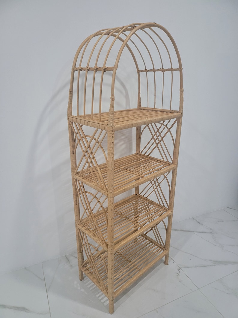 May include: A natural woven rattan shelf unit with an arched top and four shelves. The shelf unit is made of light brown rattan and has a natural finish.
