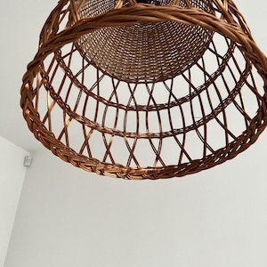 May include: A woven wicker lampshade in a warm brown color. The lampshade is round and has a decorative pattern.