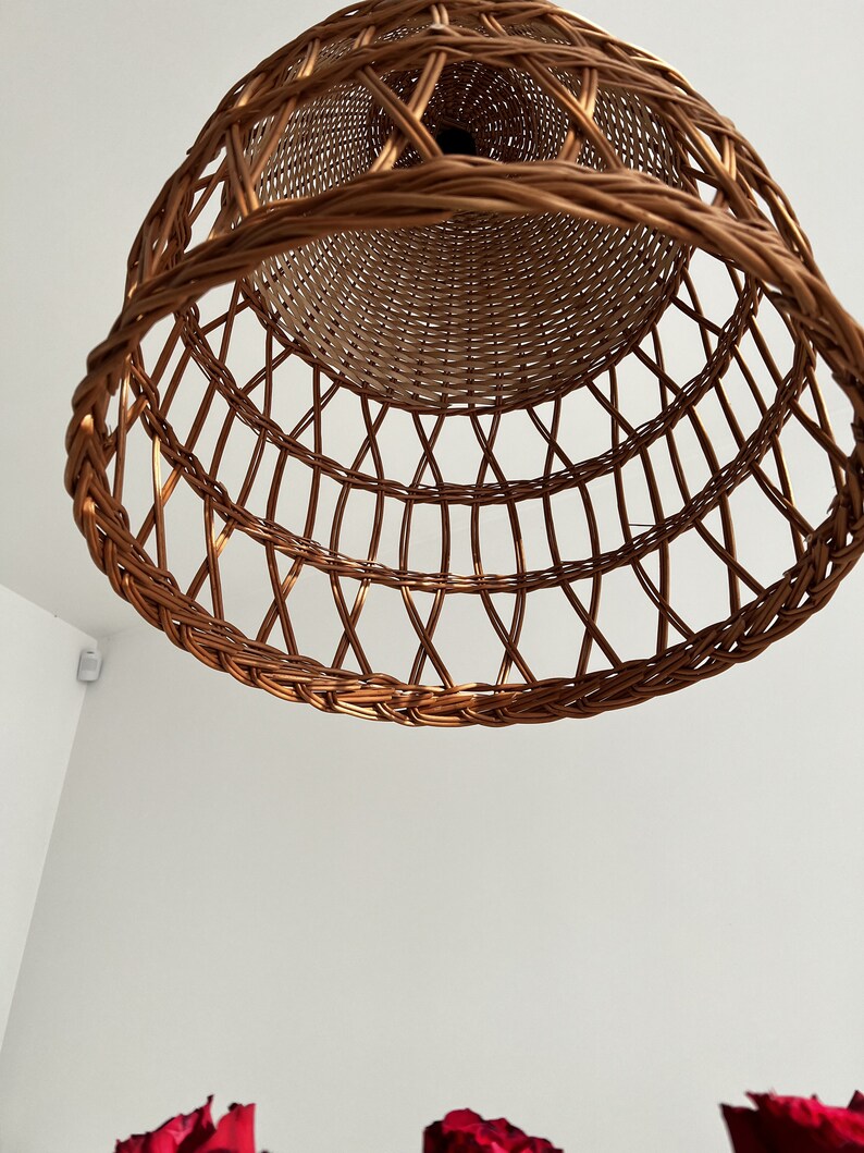 May include: A woven wicker lampshade in a warm brown color. The lampshade is round and has a decorative pattern.
