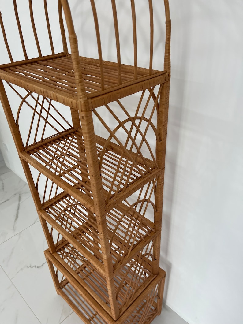 May include: A tall, natural woven wicker shelf unit with five shelves. The shelf unit has a rounded top and a woven design.