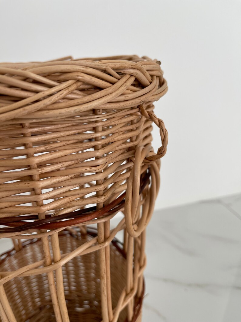 Pu&ograve; includere: Un cesto intrecciato in vimini con una fascia marrone e un manico. Il cesto &egrave; realizzato con materiali naturali e ha un aspetto rustico.