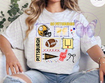 Könnte beinhalten: Ein aschgraues T-Shirt mit einem Grafikdruck mit dem Text GO PITTSBURGH und PITTSBURGH. Das Design umfasst einen Football-Helm, eine Schleife, einen Football, ein Torpfosten, einen Wimpel, einen Schaumstofffinger und Sterne in Gelb, Schwarz und Rot.