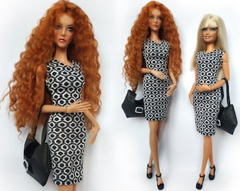 Puede incluir: Tres muñecas con vestidos de estampado geométrico en blanco y negro. Las muñecas tienen el pelo largo, dos con pelo rojo y una con pelo rubio. Cada muñeca lleva un bolso negro.