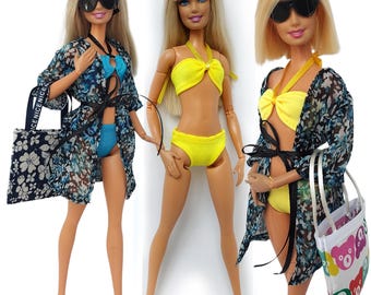 Może przedstawiać: Trzy blond lalki w okularach przeciwsłonecznych i strojach kąpielowych. Jedna lalka ma na sobie niebieskie bikini z narzutką w kwiaty i torbą. Inna lalka ma na sobie żółte bikini. Trzecia lalka ma na sobie żółte bikini z narzutką w kwiaty i torbą.