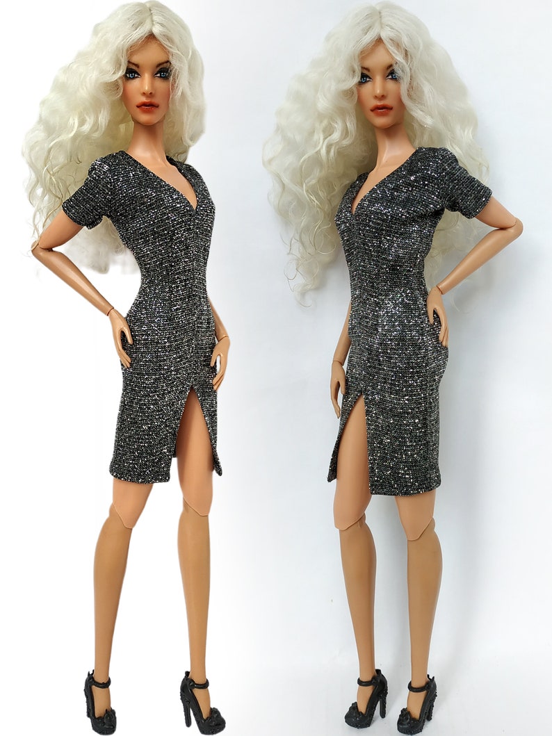 Puede incluir: Dos mu&ntilde;ecas de moda con cabello largo, blanco y rizado, que llevan un vestido plateado brillante con una abertura en la pierna y tacones negros.