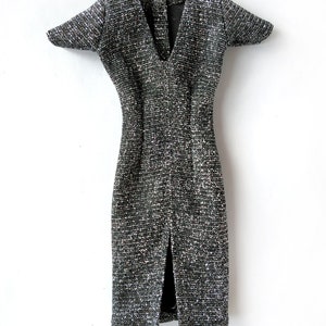 Puede incluir: Un vestido plateado y negro brillante con cuello en V y mangas cortas. El vestido tiene una abertura en la parte delantera y una silueta ajustada.