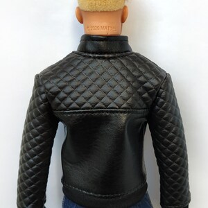 May include: Black quilted jacket with a zipper closure. The jacket has a diamond pattern and a black ribbed knit collar, cuffs, and hem. The jacket is made of faux leather and has the text "&copy;2020 MATTEL" printed on the back.
