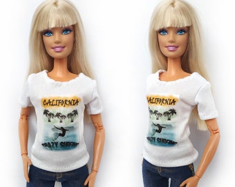 May include: Two white t-shirts with a graphic print of palm trees and a surfer with the text "CALIFORNIA CRAZY SURFING".