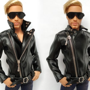 K&ouml;nnte beinhalten: Schwarze Lederjacke mit Rei&szlig;verschluss und silbernen Beschl&auml;gen. Die Jacke hat einen Stehkragen und einen G&uuml;rtel an der Taille.