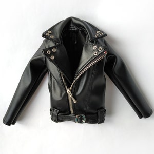 K&ouml;nnte beinhalten: Eine schwarze Lederjacke mit Rei&szlig;verschluss, G&uuml;rtel und silberfarbenen Beschl&auml;gen.