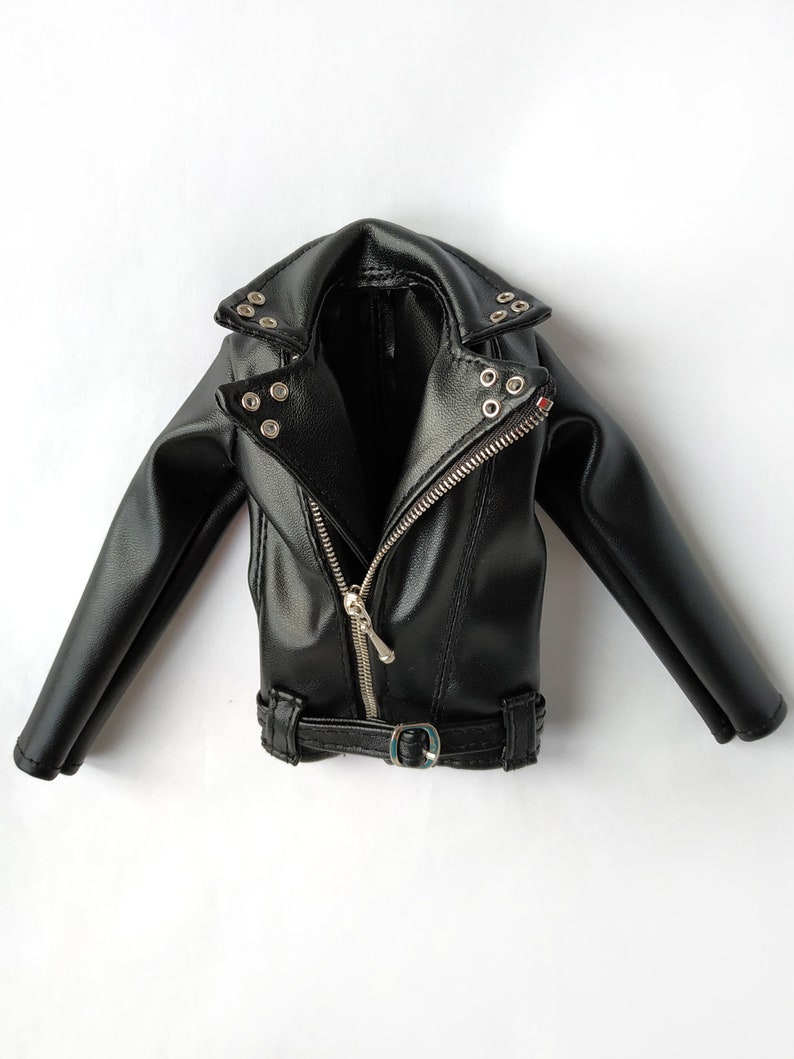 K&ouml;nnte beinhalten: Eine schwarze Lederjacke mit Rei&szlig;verschluss, G&uuml;rtel und silberfarbenen Beschl&auml;gen.