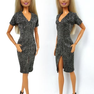 Puede incluir: Dos mu&ntilde;ecas Barbie con un vestido brillante plateado y negro con cuello en V y una abertura en el lateral. Las mu&ntilde;ecas tienen el pelo rubio y los ojos azules.