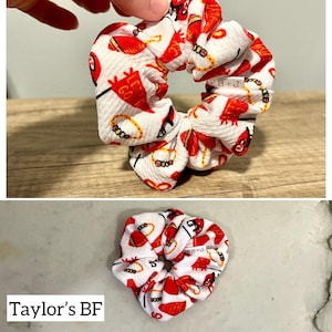May include: White scrunchie with a red and yellow print of footballs, a football helmet, and the words "Let's Go!" and "PB+J".