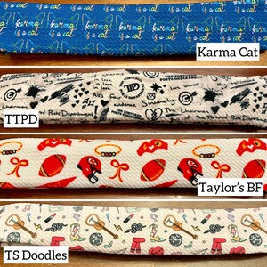 May include: Four fabric swatches with different patterns. The top swatch is blue with white text that says "Karma Cat is a cat". The second swatch is beige with black text and drawings. The third swatch is white with red and gold football helmets and footballs. The bottom swatch is white with a musical note pattern, a snake, a cowboy boot, and a disco ball.