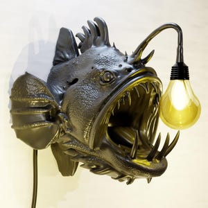 May include: A white ceramic mug with a black handle and the text "But First, Coffee" in a handwritten style. The mug is on a white surface. The mug is likely used for hot beverages.