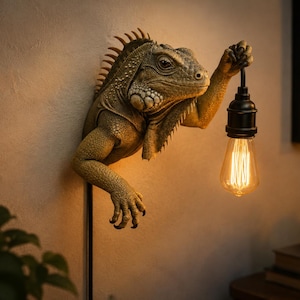 Può includere: Una lampada da parete con una scultura realistica di iguana verde. L'iguana è raffigurata con squame strutturate e una cresta spinosa, estendendo un braccio artigliato per reggere un portalampada nero con una luminosa lampadina Edison vintage.