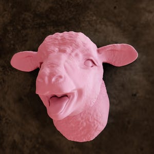 Könnte beinhalten: Eine rosafarbene Schafskopfskulptur mit offenem Mund und herausgestreckter Zunge. Die Skulptur ist an einer braunen Wand befestigt.