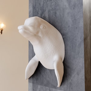 May include: White ceramic dolphin sculpture mounted on a grey wall. The dolphin is facing the right side of the image and has a textured surface.