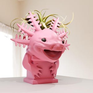 May include: A pink axolotl planter with a green plant growing out of its head. The planter is smiling and has a wide open mouth.