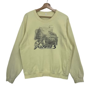 Könnte beinhalten: Hellgelbes Sweatshirt mit einem schwarz-weißen Grafikdruck, der einen Mann und japanischen Text zeigt. Der Text lautet "Siberian Express 5". Das Sweatshirt hat lange Ärmel und einen Rundhalsausschnitt.