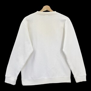 K&ouml;nnte beinhalten: Ein wei&szlig;er Pullover mit Rundhalsausschnitt und langen &Auml;rmeln.