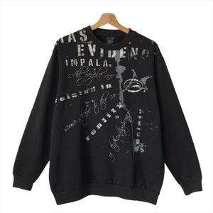 May include: Black sweatshirt with a white graphic print that says "Evidence Impala. All people are related in some shape to the core reality of the constantly evolving society."