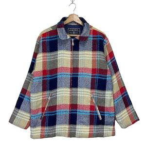 May include: A multi-colored plaid jacket with a zipper closure and two front pockets. The jacket features a mix of red, blue, beige, and gray tones. The collar is a solid gray color. The jacket is hanging on a wooden hanger.