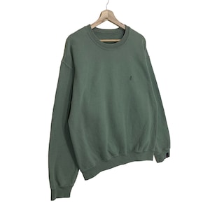 Pu&ograve; includere: Felpa girocollo verde salvia con un piccolo logo ricamato sul petto. La parte superiore a maniche lunghe &egrave; appesa a una gruccia di legno. La felpa ha orlo e polsini a coste. Il tessuto sembra essere un materiale morbido e confortevole.
