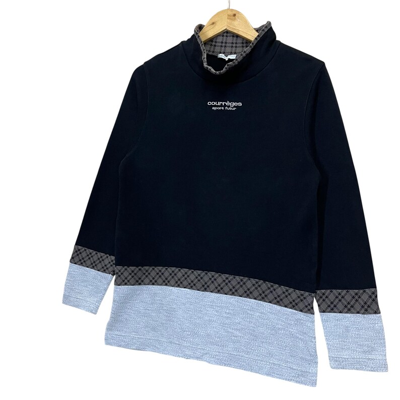 May include: Black long-sleeve sweatshirt with a high collar and gray and black plaid accents on the sleeves and lower hem. The sweatshirt has a gray lower panel and the text "courr&egrave;ges sport futur" in white.