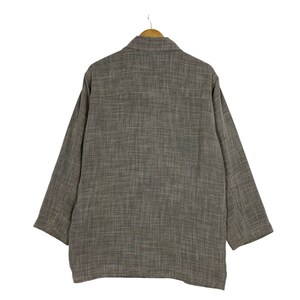 May include: A brown long-sleeved shirt with a textured pattern. The shirt is hanging on a wooden hanger.