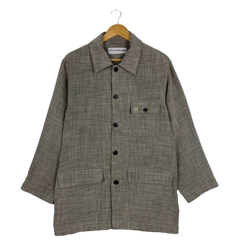 May include: A brown and gray checkered long-sleeved shirt with a button-up front and two large pockets. The shirt has a small label on the front that says "Universal Works".