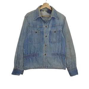 Op de afbeelding: Lichtblauwe spijkerjas met een knoopsluiting, twee borstzakken en twee lagere zakken. De jas heeft een klassieke kraag en lange mouwen met manchetten met knopen. De denim heeft een verweerde uitstraling.