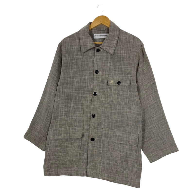 May include: A brown long-sleeved button-up shirt with a textured woven fabric. The shirt has a collared neckline, two chest pockets, and black buttons.
