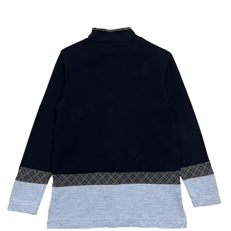 May include: A black long-sleeved shirt with a mock neck and a gray and black plaid pattern at the hem and cuffs. The lower portion of the shirt is light gray.