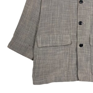May include: A brown linen jacket with a single chest pocket and two button closures.