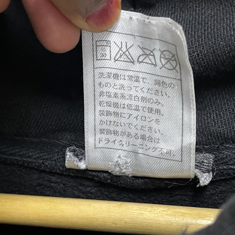 Puede incluir: Etiqueta de cuidado blanca con texto y s&iacute;mbolos negros. El texto dice: "Lavar a m&aacute;quina a temperatura normal, solo con colores similares. No usar lej&iacute;a. Secar en secadora a baja temperatura. No planchar. Limpieza en seco &uacute;nicamente."