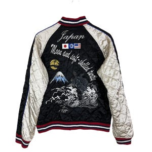 May include: Black quilted jacket with cream sleeves and red and white trim. The back has Japanese embroidery with the word "Japan", flags, a mountain, and the text "Moon and soft-shelled turtle."