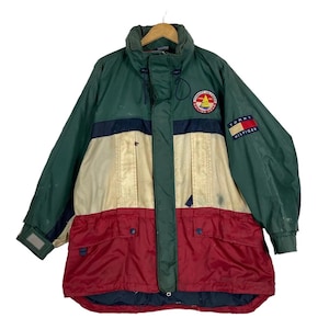 May include: A vintage green, cream, and red Tommy Hilfiger jacket. The jacket features a high collar, a zip-up front, and two front pockets. The Tommy Hilfiger logo is visible on the chest and sleeve. The jacket has a color block design.
