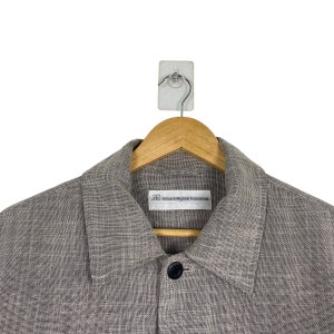 May include: A gray linen jacket with a button closure and a small label that reads "our legacy" on the left side of the chest.