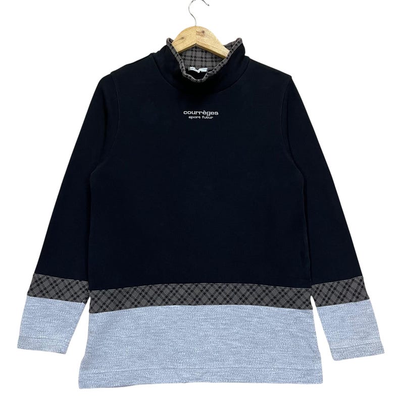 May include: Black long-sleeved sweatshirt with a high collar. The sweatshirt features a gray and black checkered pattern on the collar and hem, and a light gray bottom section. The text "courr&egrave;ges sport futur" is printed on the chest.