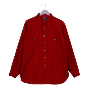 May include: A long-sleeved, red button-down shirt with two chest pockets and silver-coloured buttons. The shirt is hanging on a grey hanger against a white background. The collar is pointed, and the cuffs are buttoned.