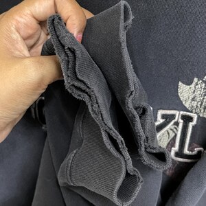 Puede incluir: Primer plano del pu&ntilde;o de canal&eacute; negro de una sudadera negra. El pu&ntilde;o est&aacute; doblado dos veces, mostrando el interior de la tela.