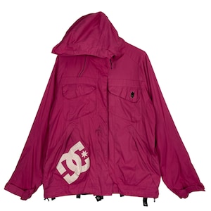 May include: A magenta hooded jacket with a white DC logo and star graphic on the front. The jacket has two chest pockets and a black button detail. The sleeves are cuffed, and the jacket is made of a lightweight material.
